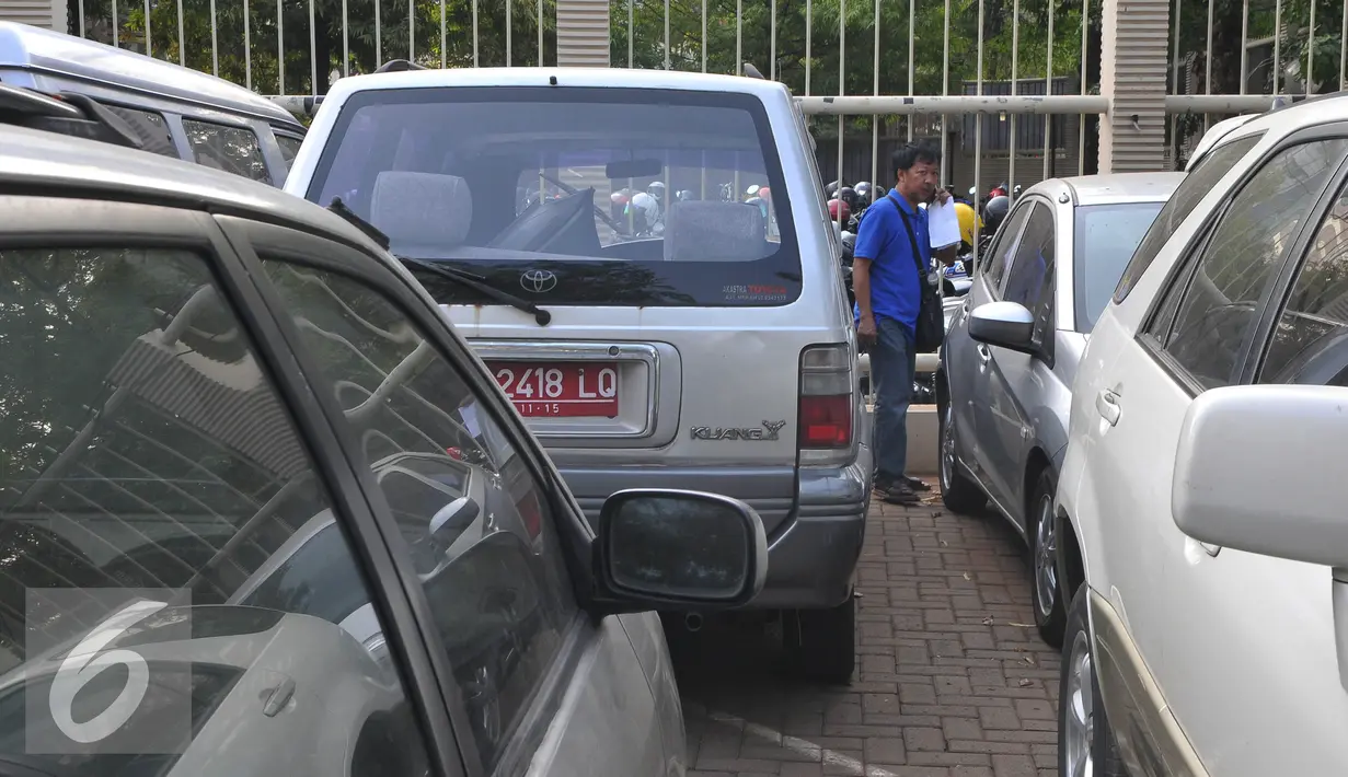 Peserta lelang mengecek mobil dinas KPK yang akan dilelang di halaman KPK, Selasa (1/9/2015). KPK akan melelang 21 mobil dan 8 motor operasional yang sudah tidak digunakan lagi pada Rabu (2/9) melalui KPKNL Jakarta III. (Liputan6.com/Herman Zakharia)