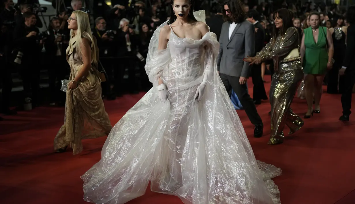 <p>Julia, 33 tahun, mengenakan korset putih berkilauan di balik gaun yang tidak biasa itu, yang harus dipegang oleh anggota timnya agar para fotografer dapat memotretnya. (Photo by Scott Garfitt/Invision/AP)</p>