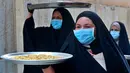 Sejumlah perempuan mengenakan masker untuk melindungi diri dari paparan virus corona COVID-19 saat membawa kue untuk perayaan Idul Fitri yang akan datang di Basra, Irak, Jumat (22/5/2020). Idul Fitri menandai berakhirnya bulan suci Ramadan. (AP Photo/Nabil al-Jurani)