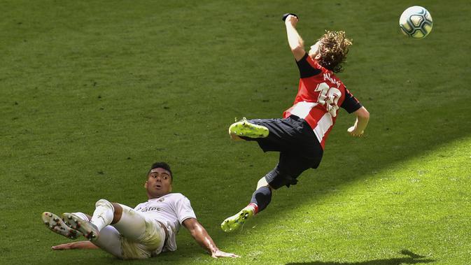 Gelandang Real Madrid, Casemiro, berebut bola dengan pemain Athletic Bilbao, Iker Muniain, pada laga La liga di Stadion San Mames, Minggu (5/7/2020). Real Madrid menang 1-0 atas Athletic Bilbao. (AP/Alvaro Barrientos)
