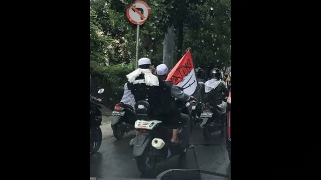 Mendera merah putih yang telah dicoret dengan tulisan Arab dan gambar silang pedang berwarna hitam.