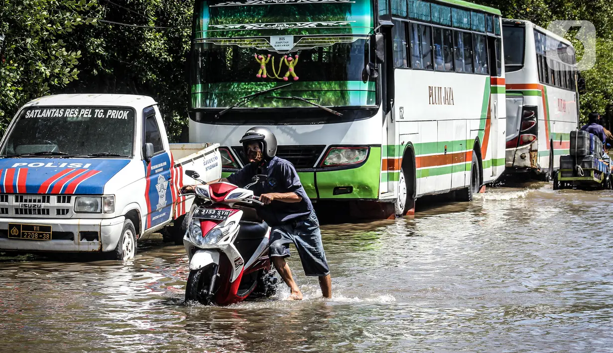 Kendaraan bermotor melintasi jalan yang tergenang air rob (banjir pasang air laut) di Kawasan Pasar Ikan Muara Baru, Jakarta, Kamis (4/6/2020). Banjir rob di Pelabuhan Muara Baru tersebut terjadi akibat cuaca ekstrem serta pasangnya air laut. (Liputan6.com/Faizal Fanani)