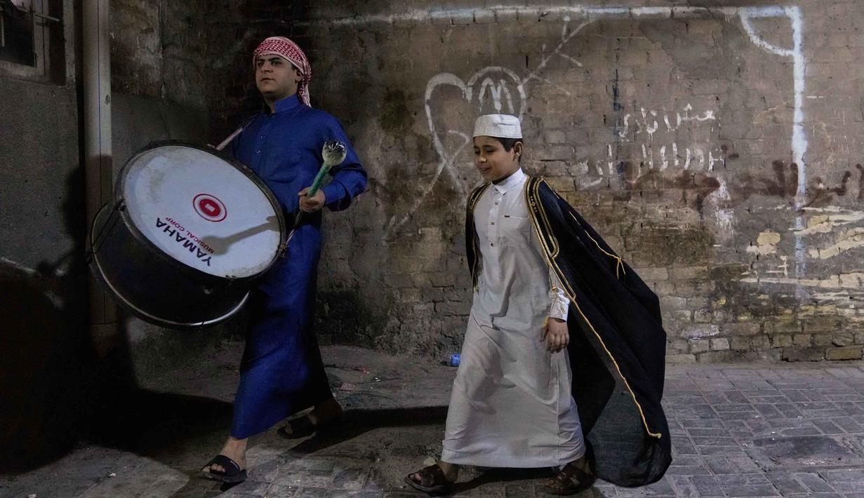 Mesaharati bertugas berkeliling di jalanan dan gang-gang kecil untuk memastikan warga tidak melewatkan waktu sahur. Tampak dalam foto, Wissam Ali, seorang "mesaharati" atau penyeru subuh berusia 22 tahun, saat membangunkan orang-orang untuk makan sebelum matahari terbit, selama bulan suci Ramadan, di lingkungan miskin distrik Fadhil di Baghdad, Irak, Senin 23 Februari 2026. (AP Photo/Hadi Mizban)