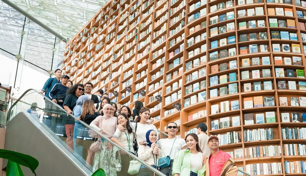 Raffi Ahmad dan Nagita Slavina berpose bersama rombongannya di tangga eskalator yang terkenal di Starfield Library. (Foto: Instagram/ raffinagita1717)