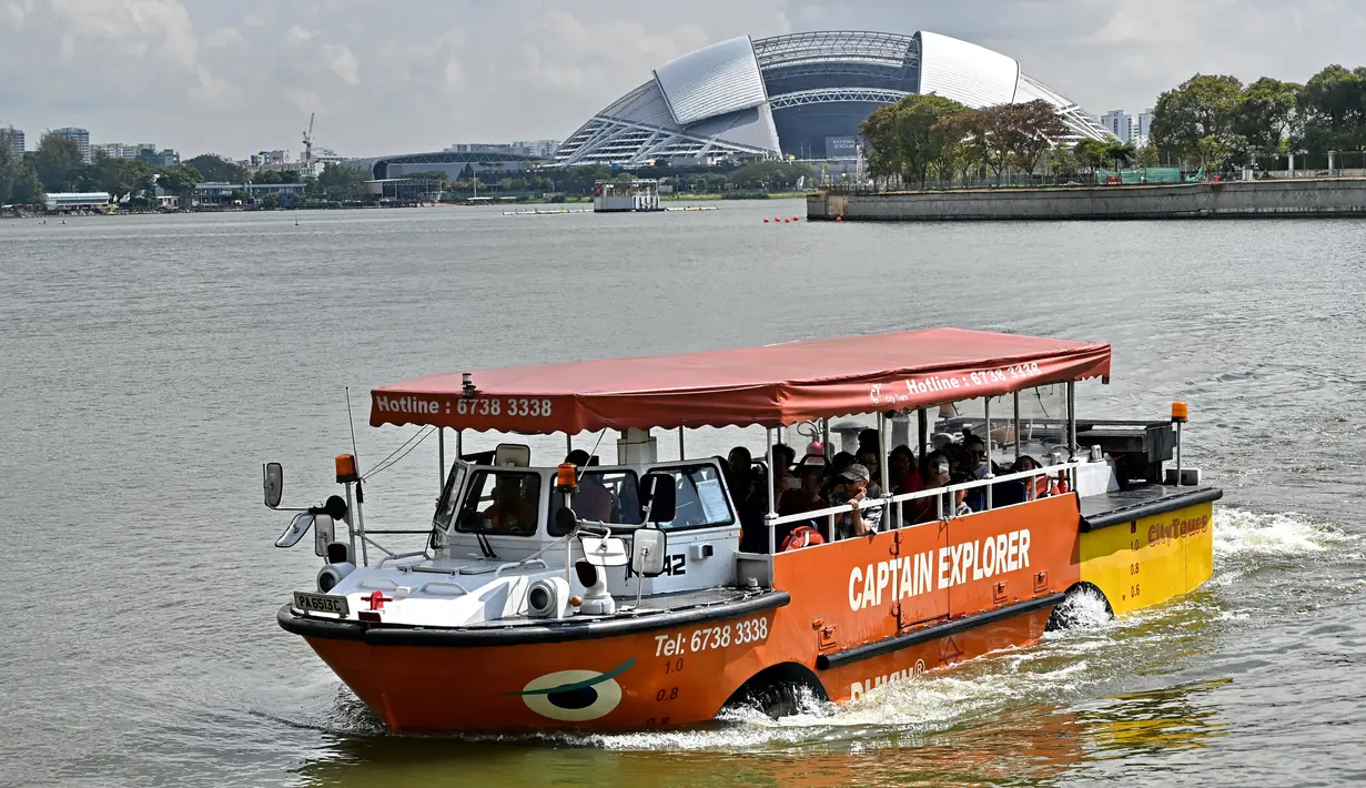 Sebuah wahana amfibi yang membawa turis melewati Stadion Nasional di Singapura pada 19 Februari 2019. Mobil-perahu mirip bebek ini mengantarkan pelancong berpetualang seru melihat keindahan Negeri Singa melalui jalur darat dan sungai. (Roslan RAHMAN/AFP)