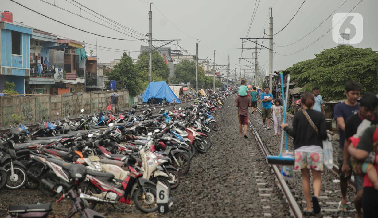 Jalur rel kereta commuterline Tangerang-Duri yang dipenuhi sepeda motor dan pengungsi banjir di Kembangan Baru, Jakarta, Jumat (3/1/2020). Jalur rel yang nonaktif sementara karena banjir dimanfaatkan warga untuk mendirikan tenda darurat karena rumah mereka masih terendam. (Liputan6.com/FaizalFanani)