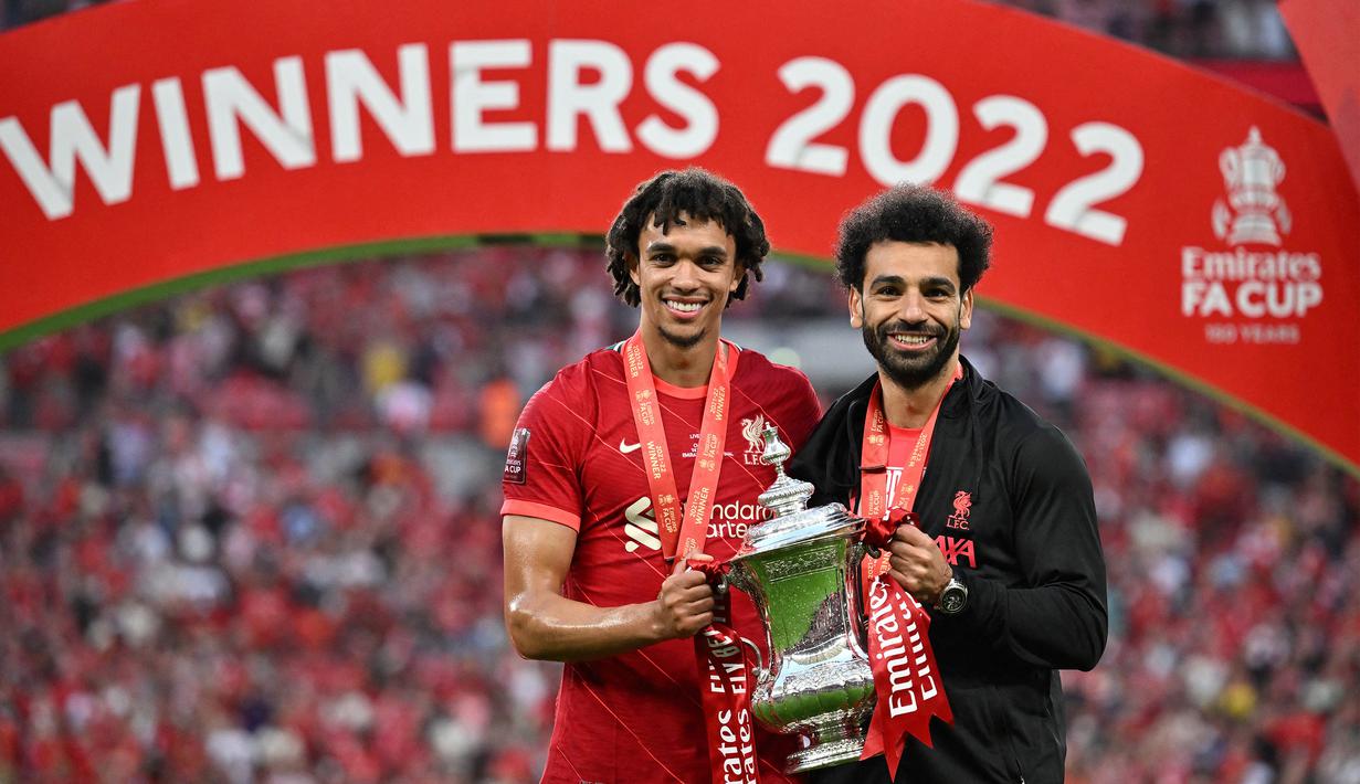 Pemain Liverpool, Trent Alexander-Arnold (kiri) dan Mohamed Salah memegang trofi Piala FA setelah mengalahkan Chelsea di final FA Cup 2021/2022 yang berlangsung di Wembley stadium, Sabtu (14/5/2022). Sejak bergulir pertama kali pada musim 1871/1872, Liverpool telah meraih 8 trofi Piala FA pada musim 1964/65, 1973/74, 1985/86, 1988/89, 1991/92, 2000/01, 2005/06, 2021/22. (AFP/Ben Stansall)