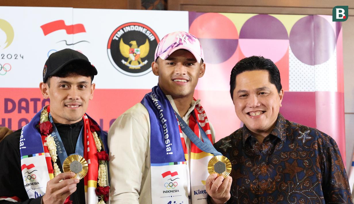 <p>Erick Thohir (kanan) bersama Atlet Indonesia peraih medali emas Olimpiade Paris 2024&nbsp;di Bandara Internasional Soekarno-Hatta, Tangerang, Selasa 13/8/2024). (Abdul Aziz/Bola.com).</p>
