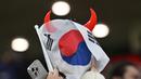 Seorang suporter Korea Selatan menutup muka menggunakan bendera negaranya setelah timnya kalah dari Yordania pada laga semifinal Piala Asia 2023 di Ahmad Bin Ali Stadium, Doha, Qatar, Selasa (06/02/2024). Korea Selatan kalah dengan skor 0-2. (AFP/Hector Retamal)