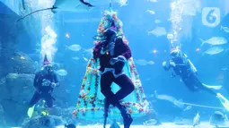 Penyelam berkostum sinterklas meyapa pengunjung di dalam air yang dihias pohon natal di Jakarta Aquarium dan Safari, Mal Neo Soho, Grogol, Jakarta, Kamis (24/12/2020). Pertunjukan ini menerapkan protokol kesehatan yang ketat untuk mencegah penularan Covid-19. (Liputan6.com/Angga Yuniar)