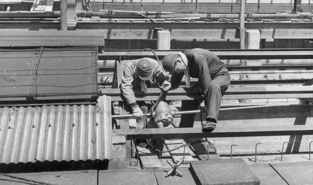 Dua pekerja Jepang sedang mengerjakan bangunan stasiun Shinagawa, Tokyo, Jepang, pada 1950. (The History). 