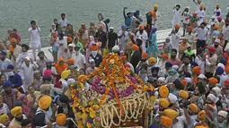 Kepala pendeta Sikh Jagtar Singh (tengah) membawa teks pokok agama Sikhisme, Guru Granth Sahib selama prosesi keagamaan dari Gurudwara Ramsar ke Akal Takht Sahib di Kuil Emas, Amritsar, India, Rabu (19/8/2020). Acara ini untuk memperingati 416 tahun pelantikan Guru Granth Sahib. (NARINDER NANU/AFP)