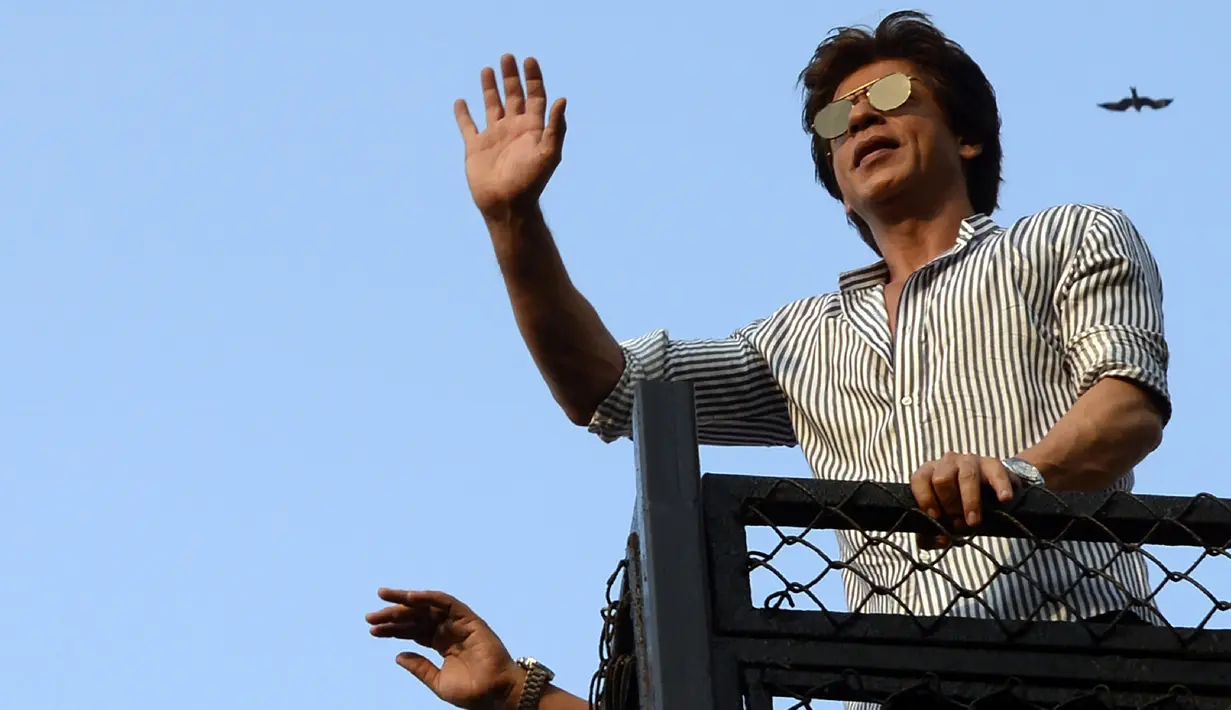 Aktor Bollywood, Shahrukh Khan melambaikan tangan kepada  para fans yang berkumpul dari balkon rumahnya di Mumbai, Kamis (2/11). Bagi warga India, datang ke kediaman SRK pada ulang tahunnya sudah menjadi tradisi penggemar. (Sujit Jaiswal/AFP Photo)