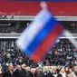 Seorang peserta mengibarkan bendera Rusia saat mendegarkan pidato Vladimir Putin dalam sebuah kampanye di stadion Luzhniki di Moskow (3/3). Putin pun telah bersiap untuk memperoleh periode keempatnya sebagai presiden Rusia. (AFP/Kirill Kudryavtsev)