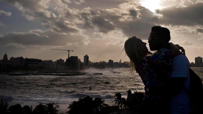 Suami istri berpelukan saaat ombak besar terlihat di laut Malecon di Havana, Kuba (21/12). Letak kota yang berdiri pada tahun 1515 ini relatif strategis. (AP Photo / Ramon Espinosa)