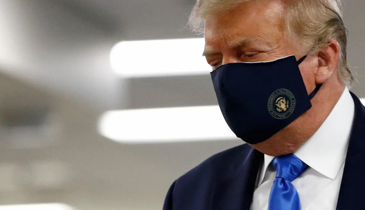 Presiden Amerika Serikat Donald Trump mengenakan masker saat menyusuri lorong dalam kunjungannya ke Pusat Kesehatan Militer Nasional Walter Reed di Bethesda, Maryland, Sabtu (11/7/2020). Trump memakai masker untuk pertama kalinya di depan umum selama pandemi COVID-19. (AP Photo/Patrick Semansky)