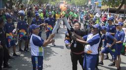 Legenda taekwondo Indonesia, Abdul Rojak, menerima obor Asian Games saat melintasi di Banjarmasin, Kalimantan Selatan, Senin (30/7/2018). Sebanyak 53 kota di Indonesia akan dilalui oleh obor Asian Games. (Bola.com/Reza Bachtiar)