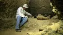 Arkeolog memeriksa mumi terbungkus kain linen di ruang pemakaman di Provinsi Minya, Mesir, Sabtu (2/2). Mumi tersebut diperkirakan berasal dari era Ptolemaic. (AP Photo/Roger Anis)