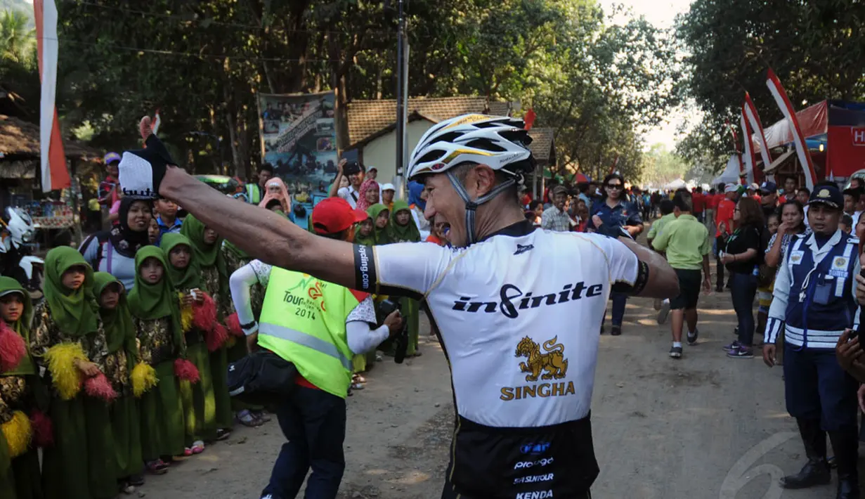 Kyosuke Takei menyapa warga sesaat setelah melintasi garis finis etape I balap sepeda International Tour de Banyuwangi Ijen, (16/10/2014). (Liputan6.com/Helmi Fithriansyah)