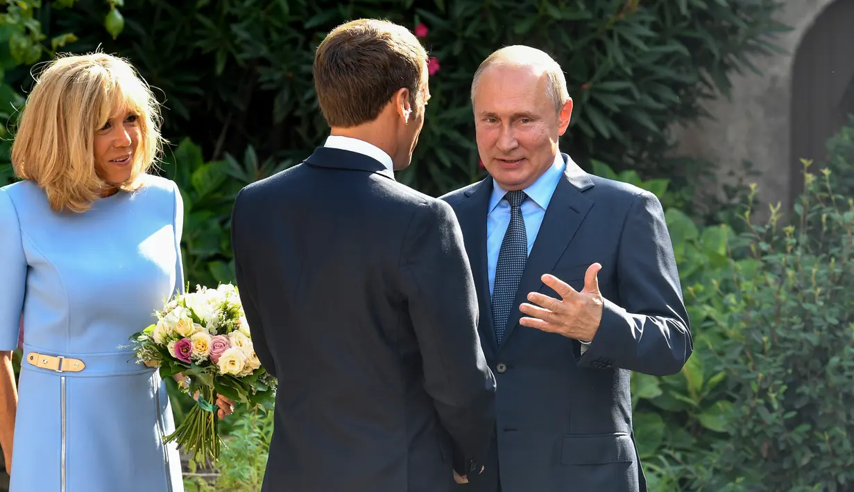 Presiden Rusia Vladimir Putin (kanan) berbincang dengan Presiden Prancis Emmanuel Macron (tengah) disaksikan Brigitte Macron di Benteng Bregancon, Bormes-les-Mimosas, Prancis, Senin (19/8/2019). Macron dan Putin mencoba meningkatkan hubungan Uni Eropa dengan Moskow. (Gerard Julien, Pool via AP)