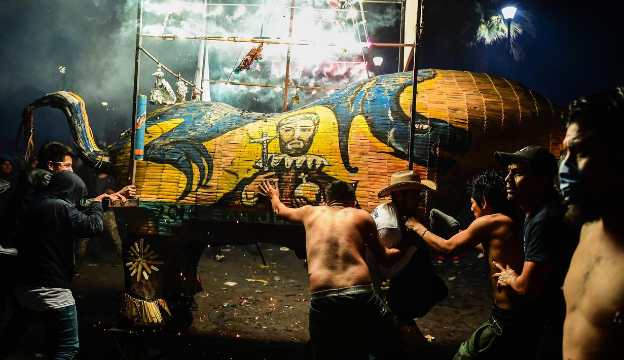 Sejumlah peserta mengarak sebuah Torito atau patung banteng yang terbuat dari kertas, kayu dan kembang api saat perayaan San Juan de Dios di Tultepec, Meksiko (8/3). (AFP Photo/Ronaldo Skemidt)