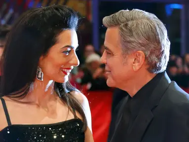 Aktor AS George Clooney dan istrinya, Amal Alamuddin berpose untuk fotografer saat tiba di karpet merah pemutaran film "Hail, Caesar!" pada pembukaan Berlin International Film Festival ke-66 di Berlin, Jerman, Kamis (11/2). (REUTERS/Fabrizio Bensch)