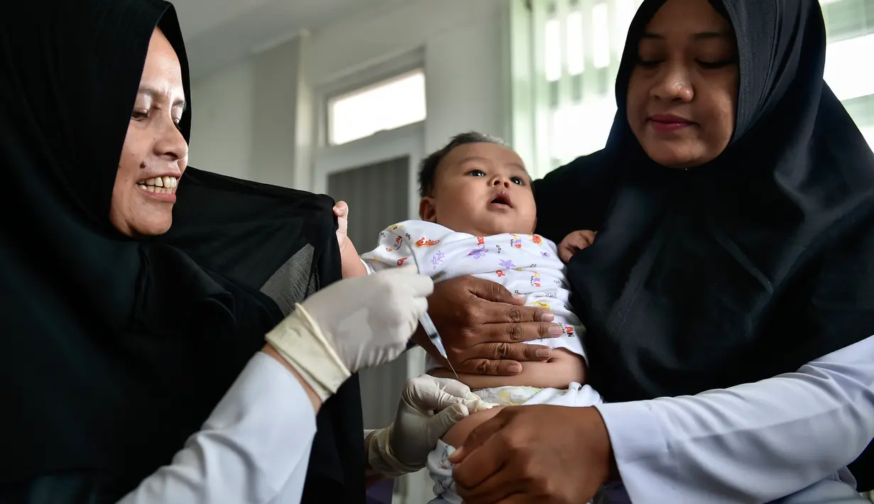 Petugas menyuntikan Vaksin Campak dan Rubella (MR) kepada bayi saat dilakukan imunisasi di sebuah puskesmas, Banda Aceh, Rabu (19/9). Pelaksanaan vaksinasi MR di Aceh sempat ditunda karena adanya enzim babi di dalam vaksin. (CHAIDEER MAHYUDDIN / AFP)