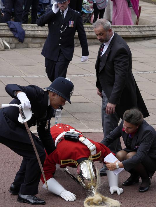 Polisi bergegas menolong seorang anggota Household Cavalry yang pingsan saat berada dalam posisi untuk upacara pertama Raja untuk Order of the Garter sebagai raja. (AP Photo/Kirsty Wigglesworth, Pool)