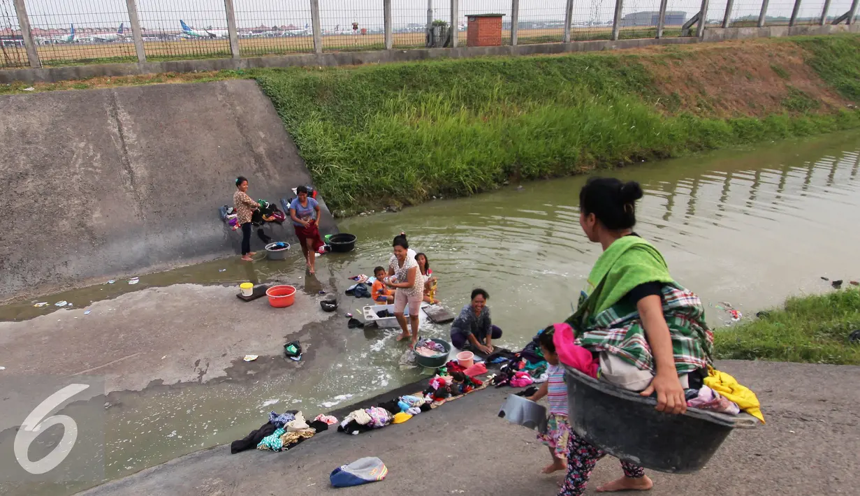 Warga mencuci pakaian di sungai yang menjadi pembatas di area Bandara Soetta, Tangerang (28/9/2015). Akibat kemarau panjang membuat pasokan air menjadi kering sehinga warga yang bermukim nekat menerobos pagar untuk mencuci. (Liputan6.com/Angga Yuniar)