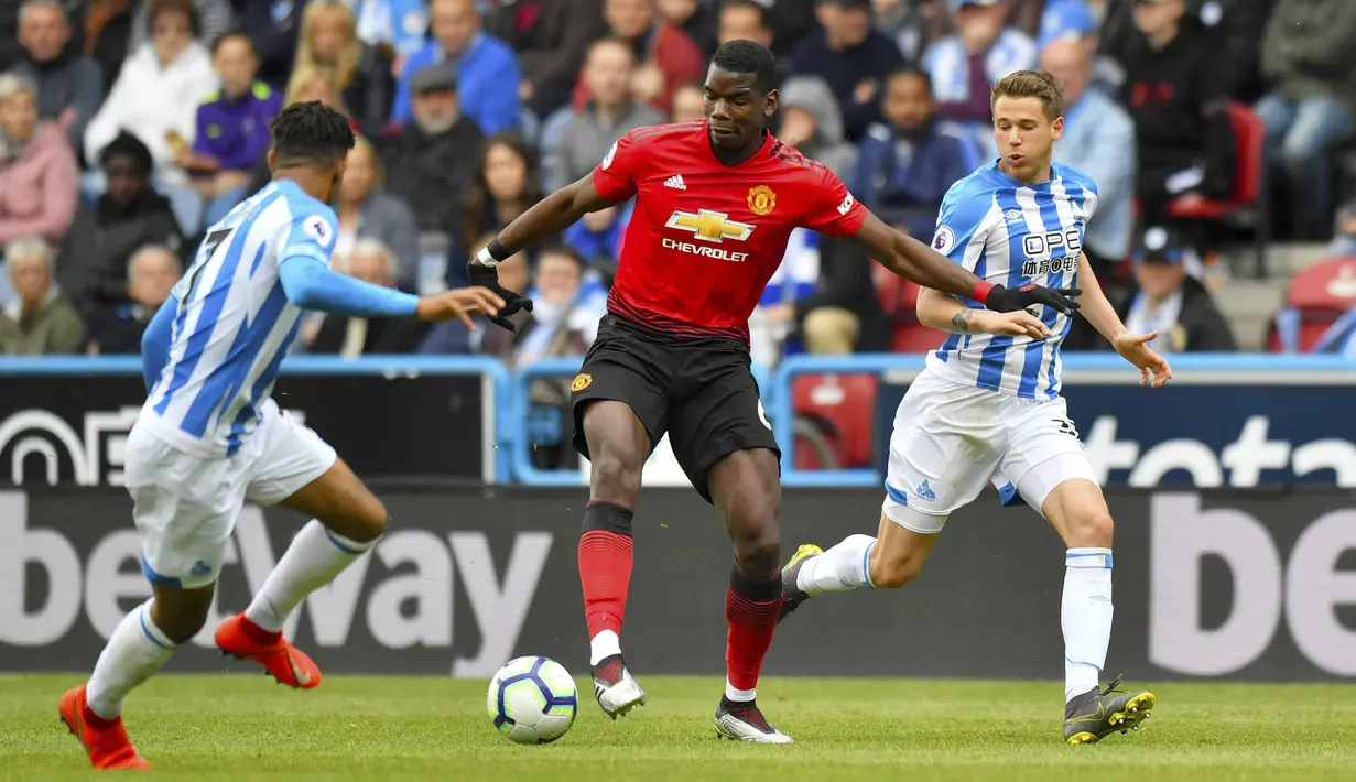 Gelandang Manchester United, Paul Pogba, berusaha melewati pemain Huddersfield Town pada laga Premier League di Stadion John Smith, Minggu (5/5). Kedua tim bermain imbang 1-1. (AP/Anthony Devlin)