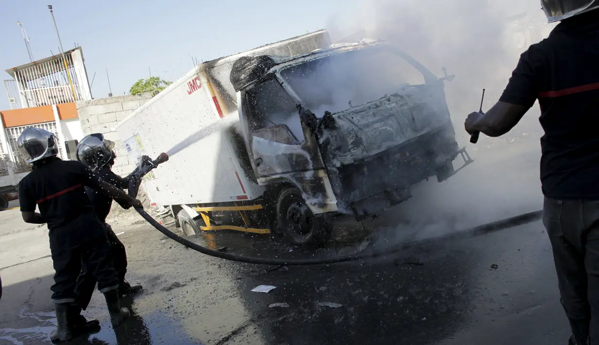 Petugas kebakaran memadamkan api yang membakar truk saat demo pemilu di Port-au-Prince, Haiti, (18/1). Warga Haiti kembali memanas setelah keputusan KPU setempat menunda pemilihan presiden ditunda hingga 24 Januari 2016. (REUTERS/Andres Martinez Casares)