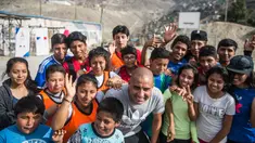 Mantan pemain bola Juventus, David Trezeguet berfoto bersama anak-anak di komunitas San Pablo Mirador, Peru (13/7). Trezeguet melakukan kunjungan ke Peru untuk mempromosikan Paris yang menjadi tuan rumah Olimpiade 2024. (AFP Photo/Ernesto Benavides)