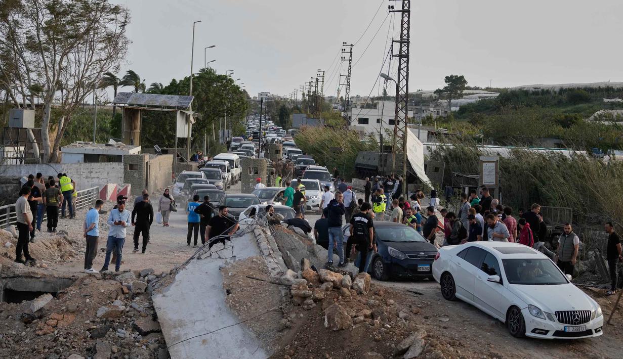 Antrean kendaraan dilaporkan terjadi di jalan-jalan menuju Lebanon Selatan, dengan banyak pengungsi membawa kembali barang-barang mereka. Tampak dalam foto, para pengungsi berjalan kembali ke desa mereka, setelah gencatan senjata antara Hizbullah dan Israel, menyeberangi jembatan Qasmiyeh yang hancur di dekat kota Tyre, Lebanon Selatan, Jumat 17 April 2026. (AP Photo/Mohammed Zaatari)
