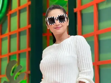 Tampil dengan busana berwarna putih, Dewi Perssik terlihat melengkapi penampilannya menggunakan kacamata hitam. Frame besar berwarna hitam putih pada kacamata ini pun menarik perhatian netizen. (Liputan6.com/IG/@dewiperssikreal.new)
