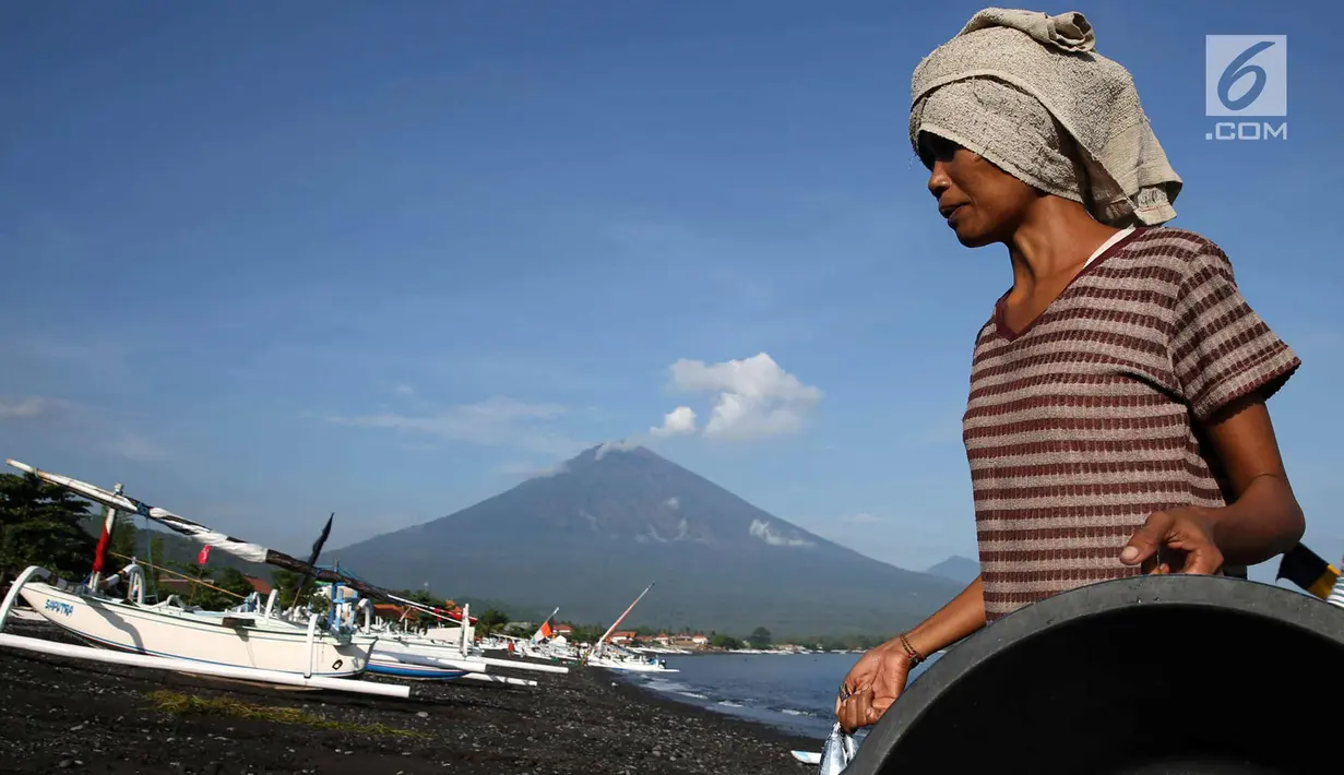Nelayan membawa hasil tangkapannya dengan latar Gunung Agung di kawasan Amed, Karangasem, Bali, Kamis (7/12). Sepekan terakhir, aktivitas Gunung Agung mulai tampak tenang, meskipun masih status Awas. (Liputan6.com/Immanuel Antonius)