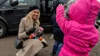 Aktris asal Kanada, Pamela Anderson memberikan buah-buahan kepada seorang anak di pengungsian Grande-Synthe, Prancis (25/1). Dalam kunjungannya, Pamela menyumbangkan buku anak-anak, makanan serta perlengkapan lainnya. (AFP/Philippe Huguen)