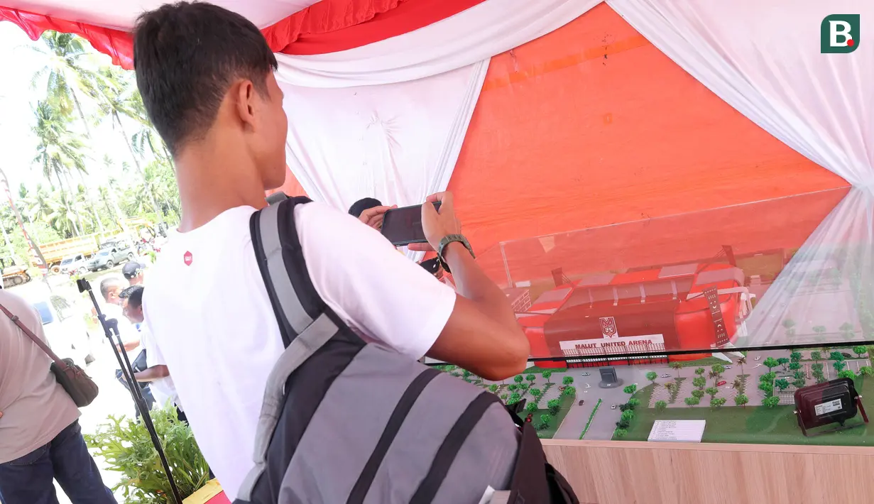 Pemain Malut United, Dedy Gusmawan, sedang memotret maket Stadion Malut United Arena dalam acara peletakan batu pertama pembangunan Stadion Malut United Arena di Kota Sofifi, Maluku Utara, Senin (14/8/2023). (Bola.com/Okie Prabhowo)