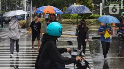 Mereka menawarkan jasa payung kepada warga yang akan melintas menembus guyuran hujan. (Liputan6.com/Angga Yuniar)