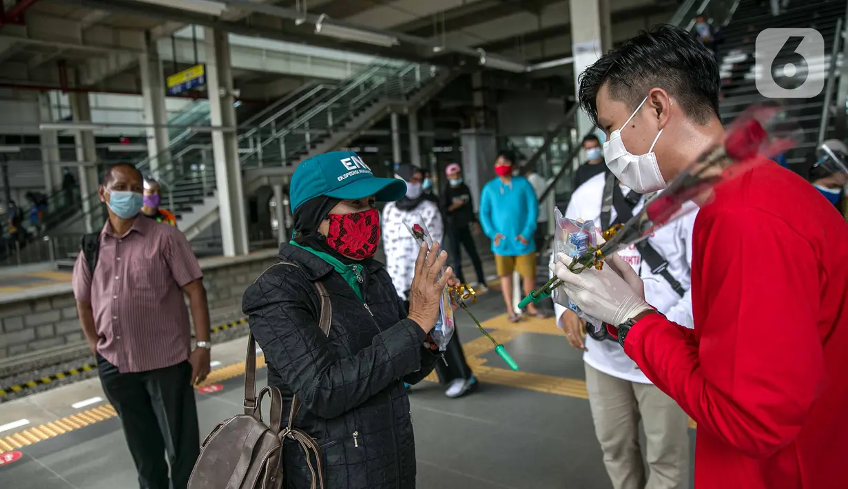 Petugas KAI Commuter (kanan) memberikan bunga dan healthy kit kepada perempuan pengguna KRL di Stasiun Jatinegara, Jakarta, Selasa (22/12/2020). Kegiatan tersebut dalam rangka memperingati Hari Ibu yang jatuh setiap tanggal 22 Desember. (Liputan6.com/Faizal Fanani)