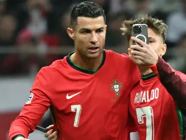 Seorang penyusup lapangan melakukan swafoto dengan pemain Portugal, Cristiano Ronaldo (kiri) saat laga lanjutan EUFA Nations League Polandia di National Stadium, Warsawa, Polandia, Minggu (13/10/2024) WIB. (AFP/Sergei Gapon)