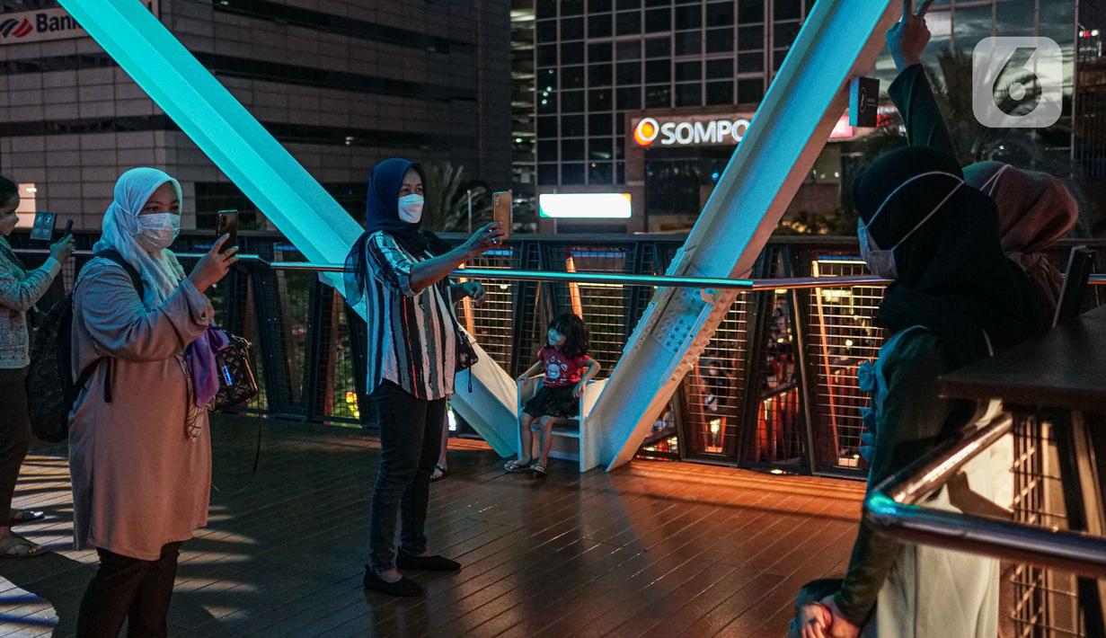Warga berfoto di balkon Jembatan Penyeberangan Orang dan Sepeda (JPOS Phinisi) di kawasan Karet, Jakarta, Minggu (20/3/2022). JPOS Phinisi kini menjadi objek baru bagi warga Jakarta. (Liputan6.com/Faizal Fanani)