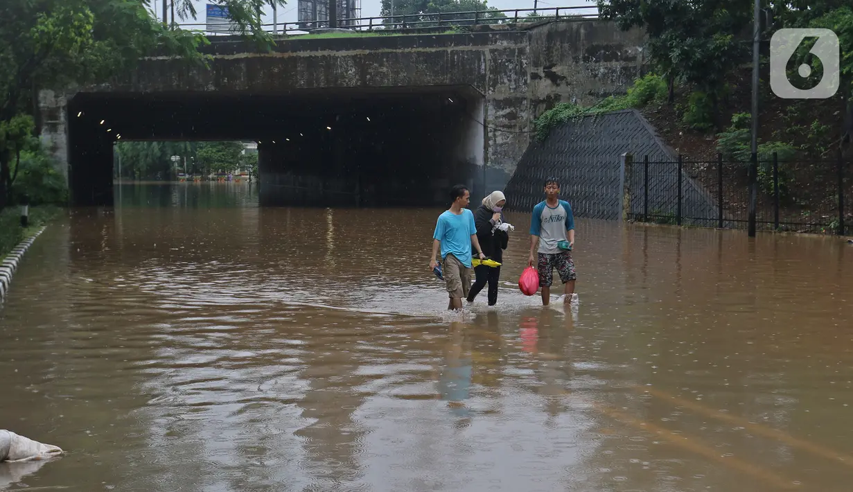 Warga berjalan kaki melintasi kawasan DI Panjaitan, Jakarta, Selasa (25/2/2020). Hujan yang mengguyur Jakarta sejak dini hari tadi membuat kawasan tersebut terendam banjir sehingga tak bisa dilintasi kendaraan bermotor. (Liputan6.com/Herman Zakharia)