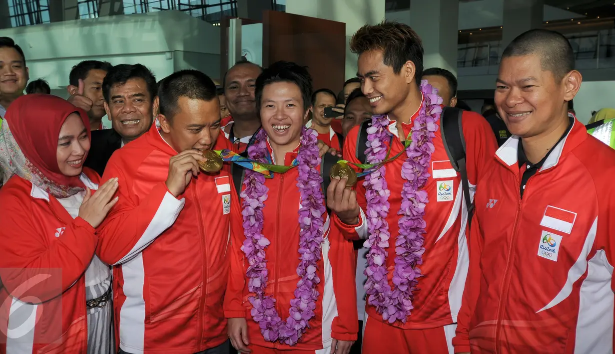Menpora Imam Nahrawi menggigit medali emas saat menyambut kedatangan Tontowi  Ahmad dan Lilyana Natsir di Bandara Soetta, Banten, Selasa (23/8/2016). Tontowi Ahmad/Lilyana Natsir berhasil meraih emas olimpiade Rio 2016. (Liputan6.com/HelmiFithriansyah)