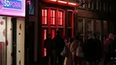 Orang-orang berjalan melewati rumah bordil di Red Light District Amsterdam, Belanda, Rabu (3/4). Pekerja seks komersial (PSK) di lokasi prostitusi tersebut mulai muak dengan turis karena dianggap sebagai atraksi wisata. (REUTERS/Yves Herman)