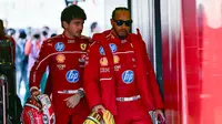 Pembalap Ferrari asal Inggris, Lewis Hamilton (kanan), dan rekan setimnya, pembalap Monako, Charles Leclerc, tiba di sirkuit pada hari pertama uji coba pramusim Formula Satu di Sirkuit Internasional Bahrain di Sakhir pada 26 Februari 2025. (Giuseppe CACACE/AFP)