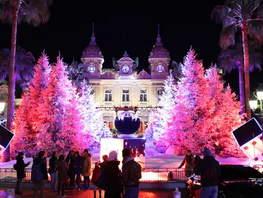 Orang-orang mengunjungi lampu dan dekorasi untuk menyambut Natal yang menghiasi depan Kasino Monte-Carlo di Monako pada 7 Desember 2018. (Photo by VALERY HACHE / AFP)