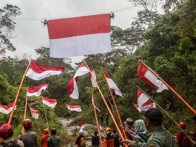 Personel Badan Pencarian dan Pertolongan Nasional (Basarnas) memasang bendera Merah Putih yang digantung pada tali yang membentang di atas sungai di Watu Kemloso, Yogyakarta, pada 13 Agustus 2025, menjelang peringatan ke-80 Hari Kemerdekaan Indonesia. (DEVI RAHMAN/AFP)