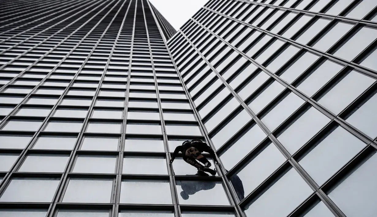 Pendaki Alain Robert atau French Spiderman memanjat Menara Total di kawasan bisnis La Defense, Paris, Prancis, Senin (13/1/2020). Hingga saat ini, pria berusia 57 tahun tersebut sudah memanjat lebih dari 100 bangunan di dunia. (Thomas SAMSON/AFP)