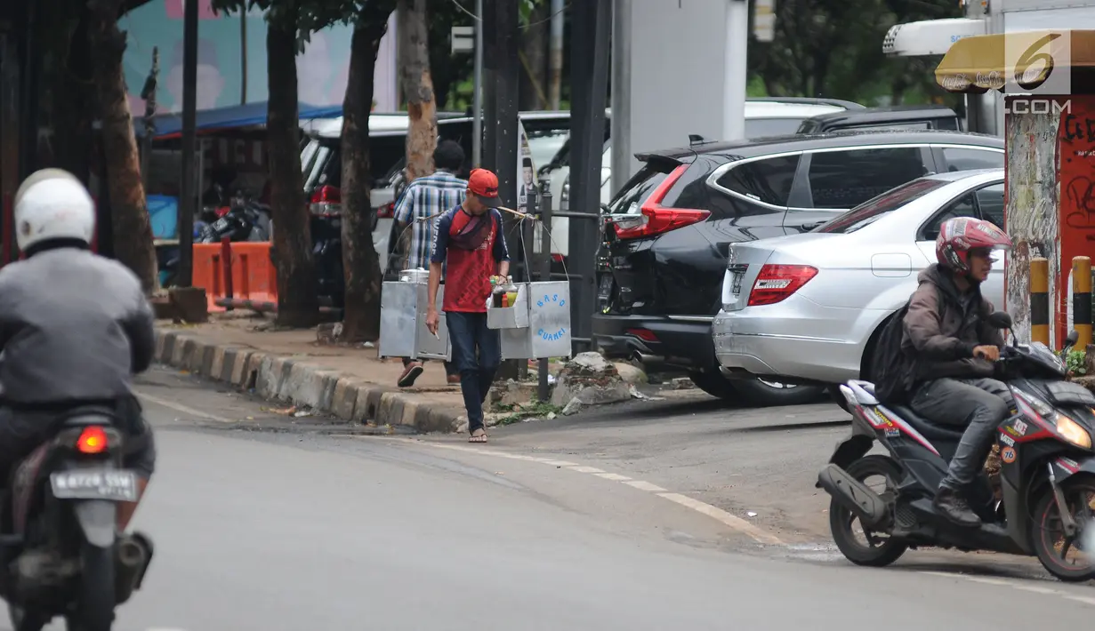 Pedagang berjalan di trotoar kawasan Kemang, Jakarta, Kamis (21/2). Trotoar di Kemang, Jakarta Selatan akan dibangun lebih lebar sehingga ramah pejalan kaki.  (Liputan6.com/Herman Zakharia)