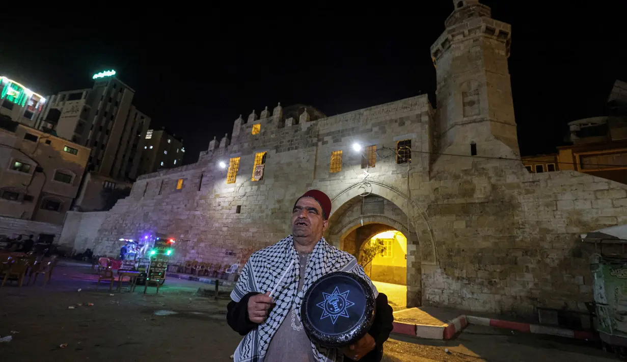 Nizar al-Dabbas Palestina berusia lima puluh tahun, seorang "Musaharati" yang memainkan peran tradisional sebagai "penabuh drum Ramadhan", membangunkan umat Islam untuk makan sahur sebelum fajar selama bulan suci Ramadhan di Khan Yunis di Jalur Gaza selatan (5/4/2022). (AFP/Said Khatib)